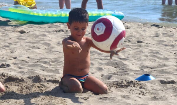 Child with Rattle ball on the beach - Real Eyes Sport, Italy